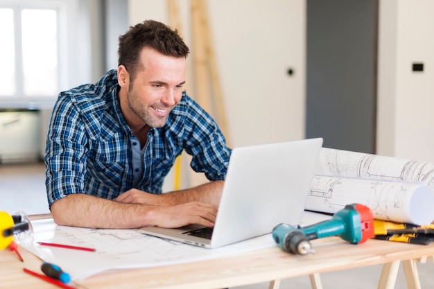 Operaio edile sorridente che lavora con il computer portatile