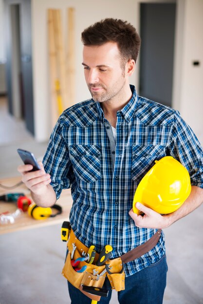 Operaio edile utilizzando il telefono cellulare durante il lavoro