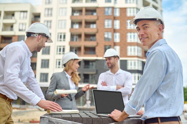 Operaio in piedi tra i suoi tre colleghi in cantiere