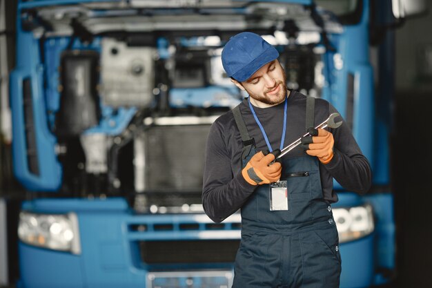 Operaio in uniforme. L'uomo ripara un camion. Uomo con strumenti