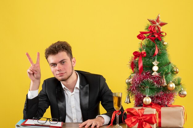 Operaio maschio vista frontale dietro il suo posto di lavoro con regali su giallo