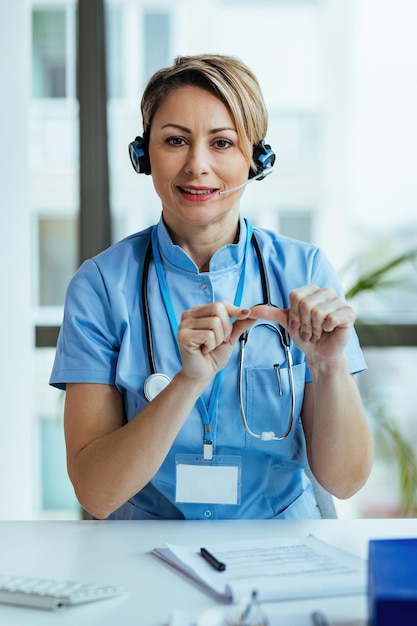 Operatore sanitario femminile che consiglia ai pazienti mentre lavora al call center dell'ospedale e guarda la fotocamera