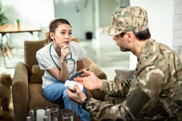 Operatore sanitario femminile che parla con un militare mentre fa consulenza a casa sua