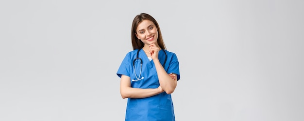 Operatori sanitari sanitari covid19 e concetto di vaccinazione ottimista sorridente bella infermiera medico in blu scrub clinica di lavoro guardando con sguardo entusiasta fotocamera che ascolta il collega