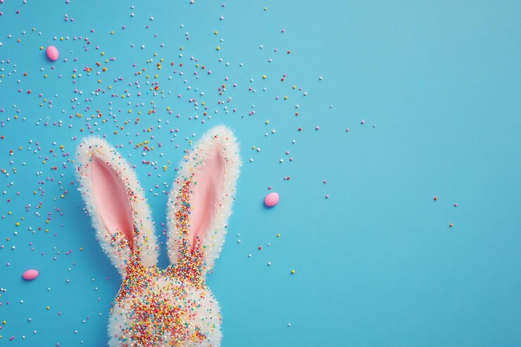 Foto gratuito orecchie di coniglietto di pasqua ricoperte di caramelle pastello spruzzate su sfondo blu