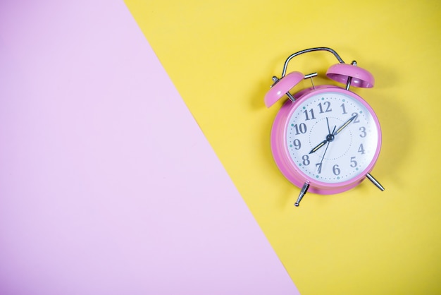 Orologio rosa sullo sfondo colorato, concetto di educazione