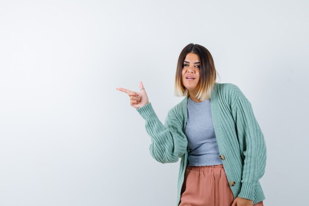 Ortrait di donna che punta a sinistra in abiti casual e guardando fiducioso vista frontale