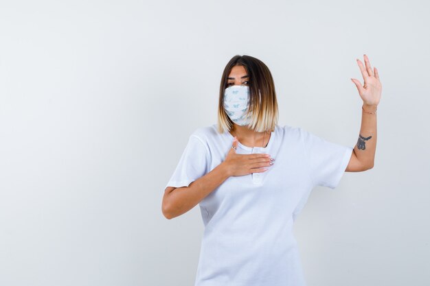 Ortrait di giovane femmina che mostra il gesto di arresto in t-shirt, maschera e che sembra seria vista frontale