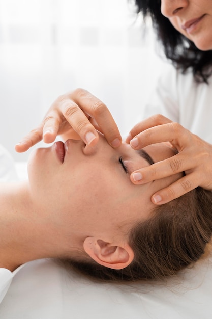 Osteopata femminile che cura un paziente massaggiando il suo fronte