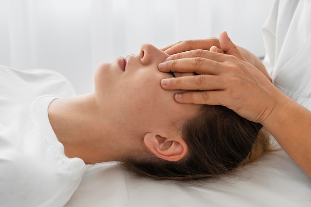 Osteopata femminile che cura un paziente massaggiando il suo fronte