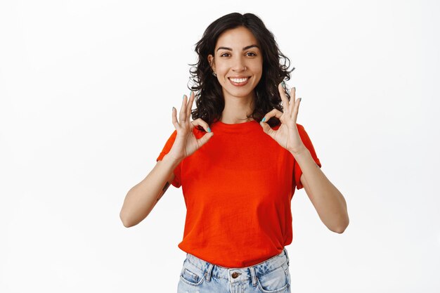 Ottimo lavoro, bravo. La donna soddisfatta sorridente fa i complimenti, mostra il gesto OK OK e annuisce in segno di approvazione, d'accordo o mi piace, loda la tua scelta, sfondo bianco