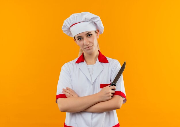 P giovane piuttosto cuoco in uniforme da chef isolato su uno spazio arancione