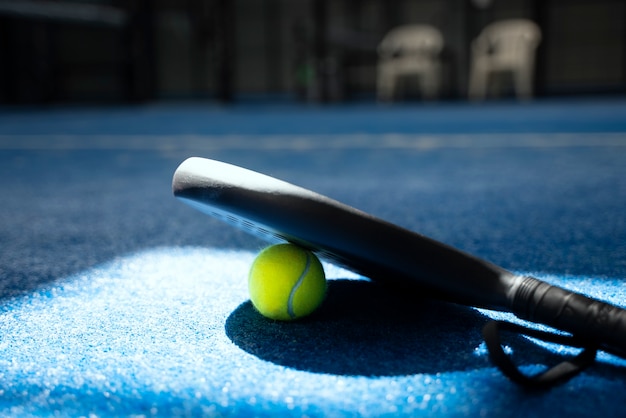 Paddle tennis tavolozza e palla sul pavimento