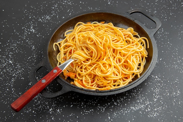 Padella per spaghetti vista dal basso su sfondo scuro