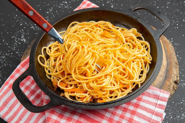 Padella per spaghetti vista dal basso su tavola di legno su sfondo scuro