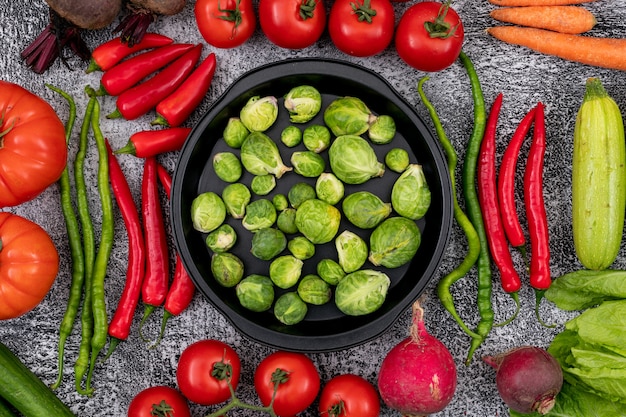 padella piena con cavoletti di Bruxelles, circondato da verdure colorate su un polveroso