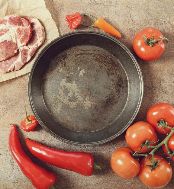 padella vuota con verdure e carne cruda intorno, vista dall'alto