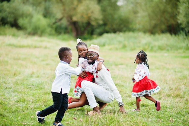 Padre africano con bambini in abiti tradizionali al parco