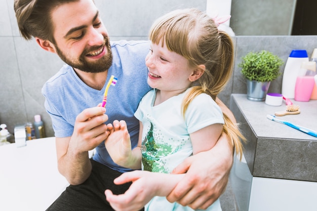 Padre allegro e figlia che puliscono i denti