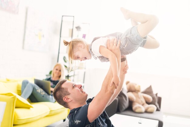 Padre che alza la figlia felice a casa