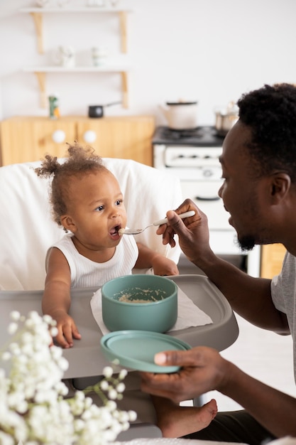 Padre che dà da mangiare alla sua piccola bambina in cucina