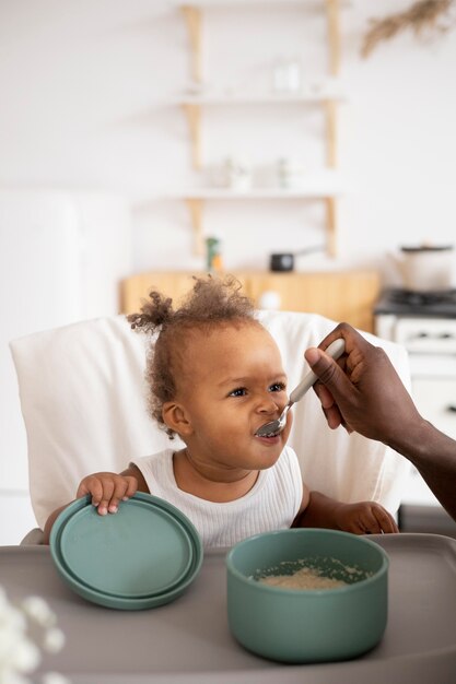 Padre che dà da mangiare alla sua piccola bambina in cucina