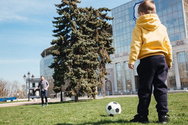 Padre che gioca a calcio con il suo piccolo figlio all'aperto nel parco.