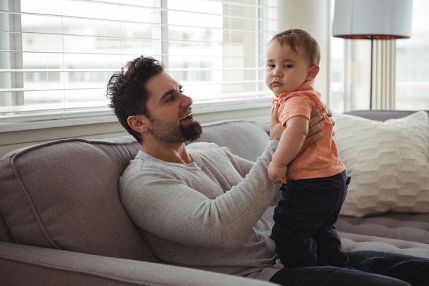 Padre che gioca con il suo bambino sul divano nel soggiorno