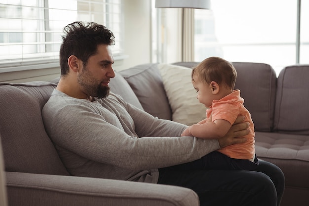 Padre che gioca con il suo bambino sul divano nel soggiorno