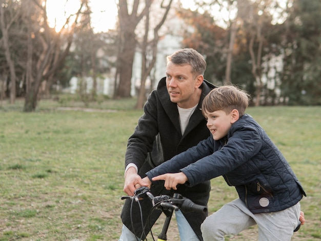 Padre che insegna a suo figlio come andare in bicicletta nel parco