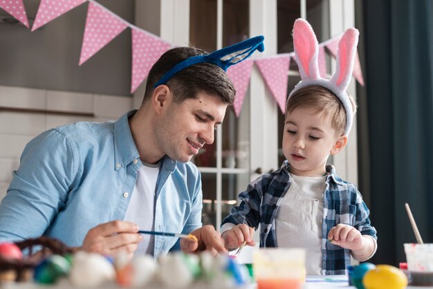 Padre che insegna a suo figlio come dipingere le uova per pasqua