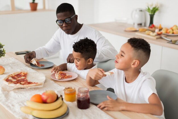 Padre che mangia insieme pizza con i suoi figli