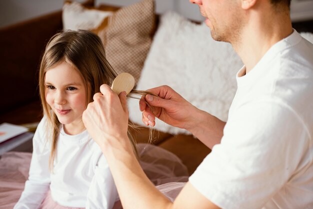 Padre che spazzola i capelli di sua figlia