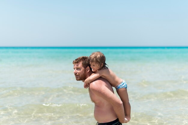 Padre che tiene il figlio in spiaggia