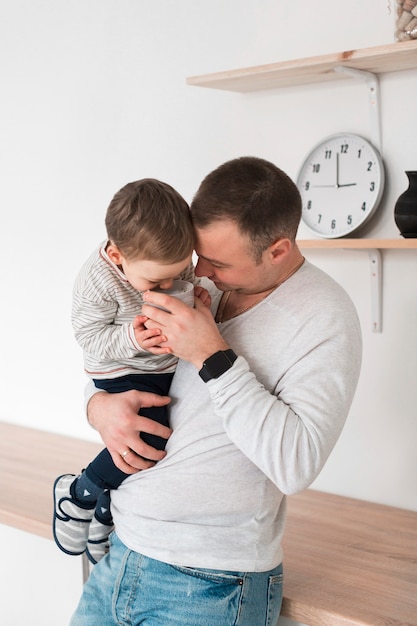 Padre che tiene il suo bambino e la tazza in cucina