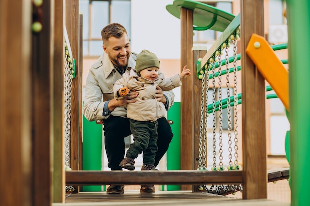 Padre con figlio bambino nel parco giochi divertendosi