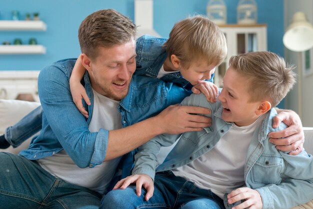 Padre con fratelli che scherzano al chiuso