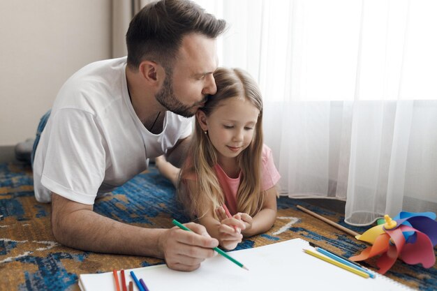 padre con la piccola figlia carina che disegna a casa