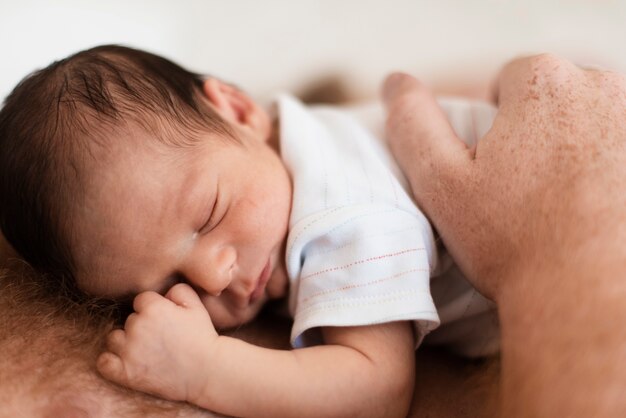 Padre del primo piano che tiene bambino sul suo petto