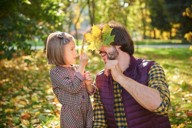 Padre e figlia che raccolgono foglie autunnali