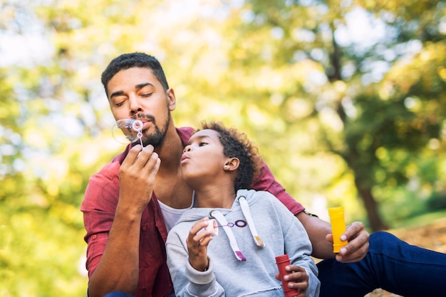 Padre e figlia che soffia bolle di sapone che godono insieme