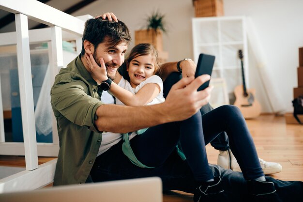 Padre e figlia spensierati si fanno selfie nella loro nuova casa