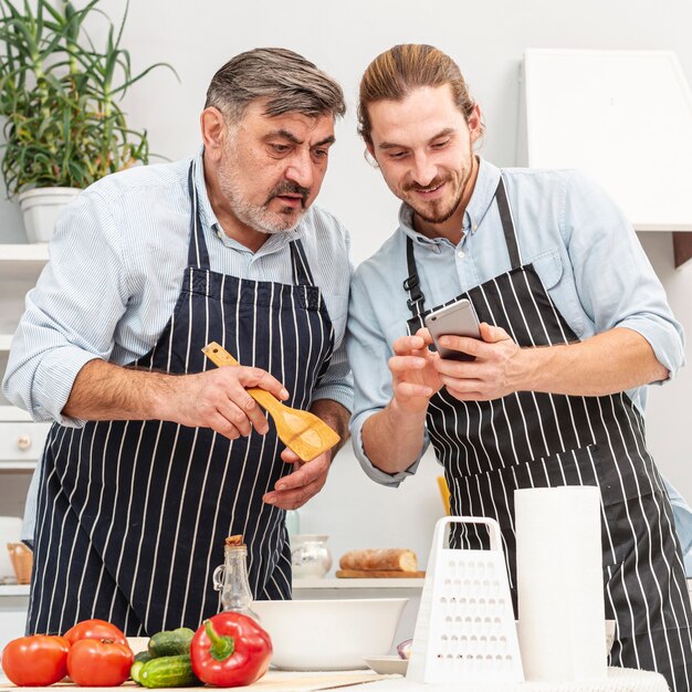 Padre e figlio alla moda che osservano sul telefono