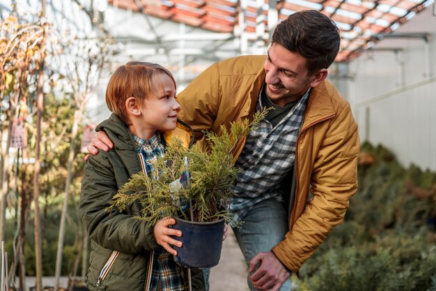 Padre e figlio che comprano insieme un piccolo albero