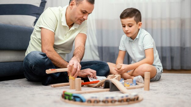 Padre e figlio che giocano con i giocattoli in camera da letto