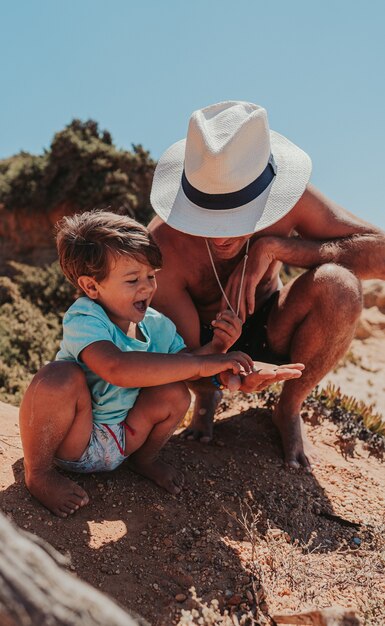 Padre e figlio che giocano felicemente sulla spiaggia sabbiosa