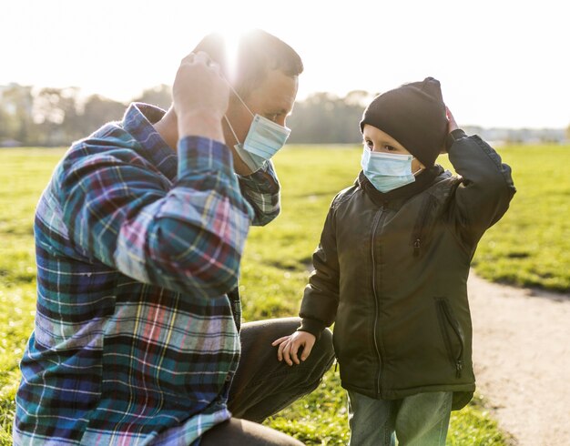 Padre e figlio che indossano maschere mediche all'aperto