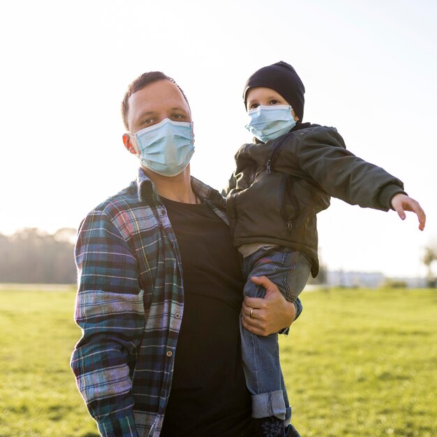 Padre e figlio che indossano maschere mediche nel parco