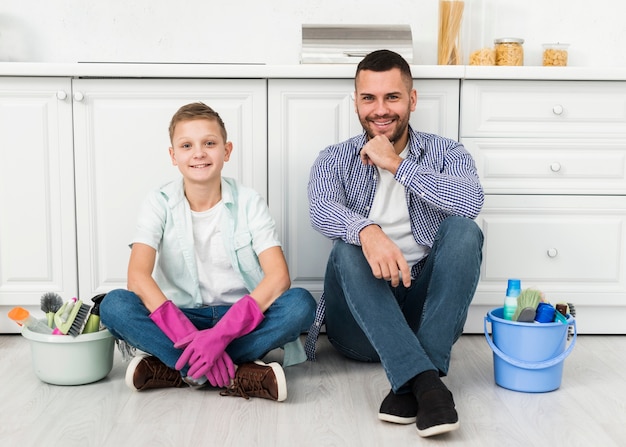 Padre e figlio che posano durante la pulizia della casa con i prodotti