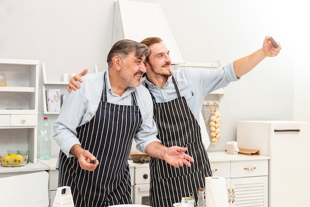 Padre e figlio che prendono un selfie in cucina